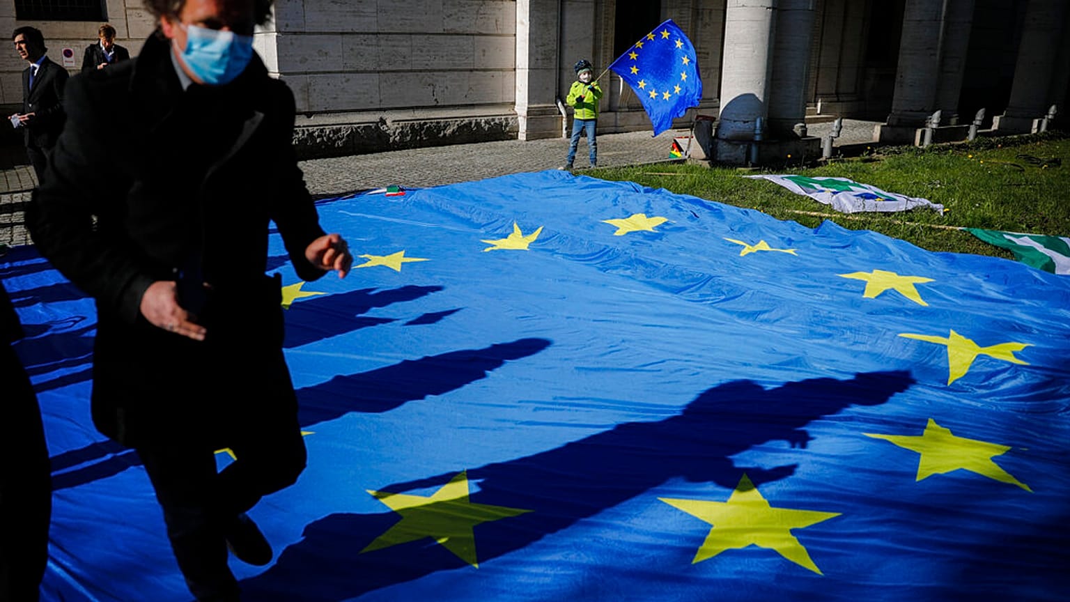 In this Wednesday, April 22, 2020 file photo, a man with a face mask and a child with an European flag attend an event of the Pulse of Europe movement.