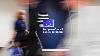 People walk by a sign in English and French in the press room at an EU summit in Brussels on Tuesday, June 28, 2016. 