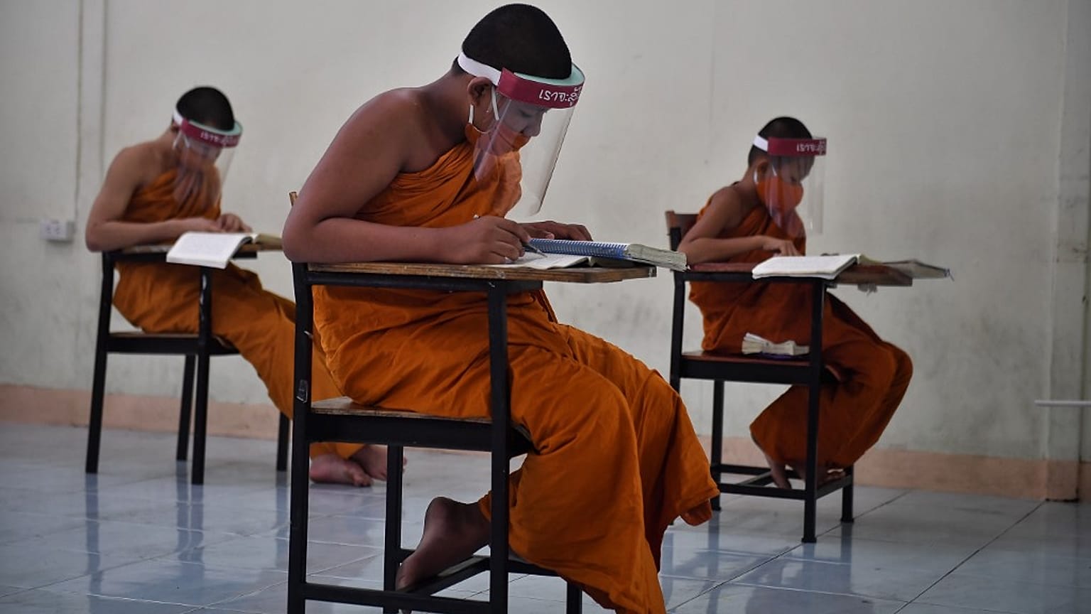 Novice monks wearing face shields in Buddhist temple in Bangkok on April 20, 2020. (Photo by Lillian SUWANRUMPHA / AFP)