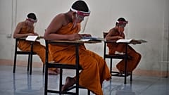 Novice monks wearing face shields in Buddhist temple in Bangkok on April 20, 2020. (Photo by Lillian SUWANRUMPHA / AFP)