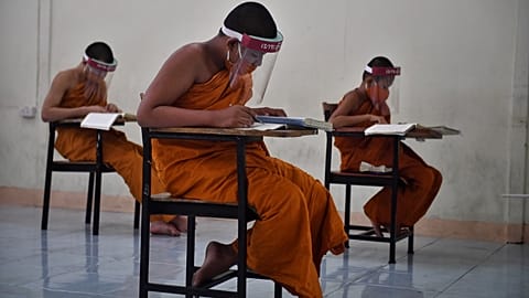 Novice monks wearing face shields in Buddhist temple in Bangkok on April 20, 2020. (Photo by Lillian SUWANRUMPHA / AFP)