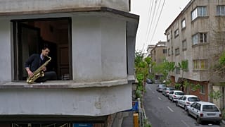 In this Wednesday, April 8, 2020 photo, Mohammad Maleklee, 23, of the National Orchestra of Iran and Tehran Symphony, plays saxophone in his window