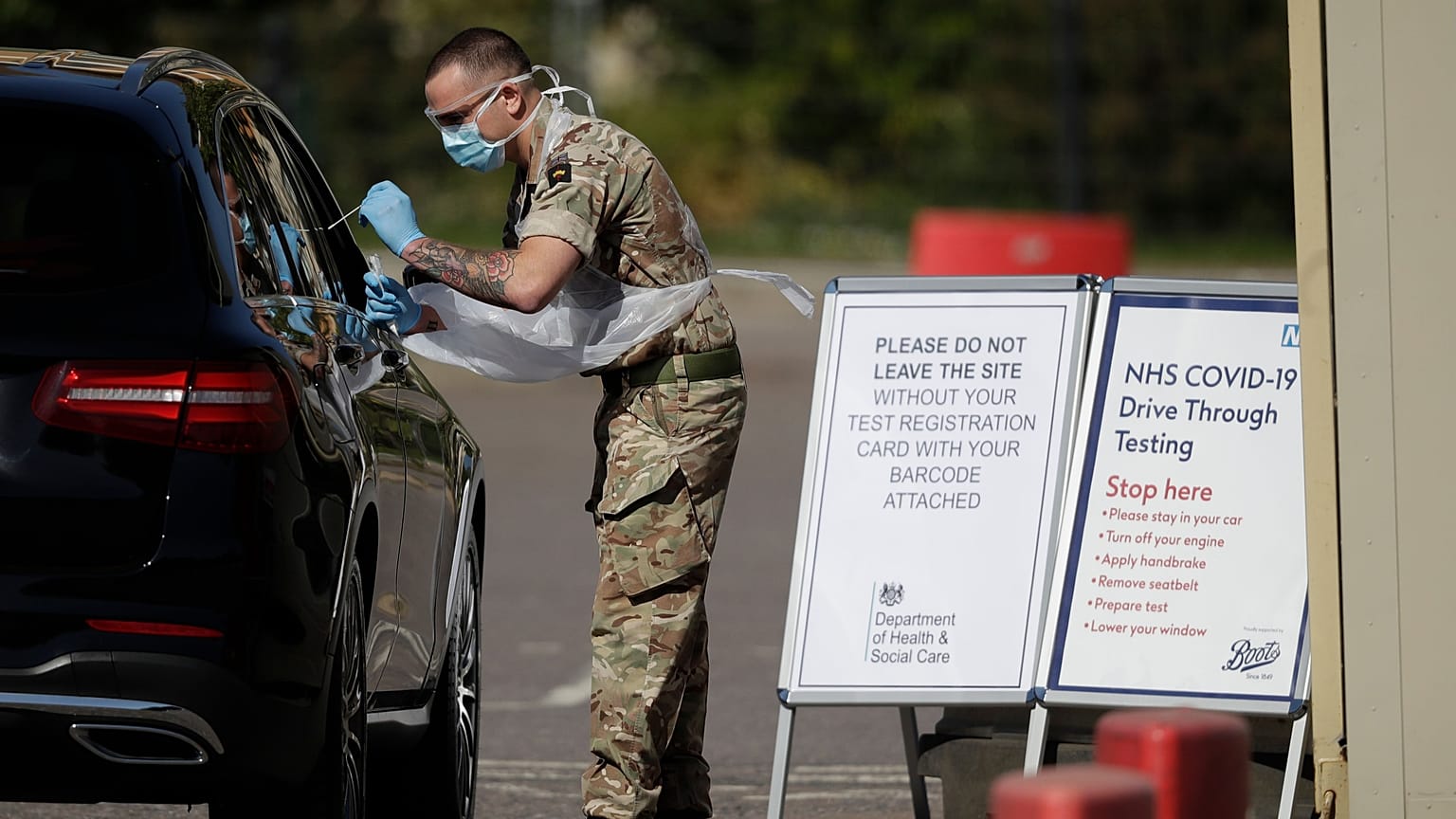 A soldier gives does a COVID-19 test at a drive-through testing centre at Chessington World of Adventures, Greater London