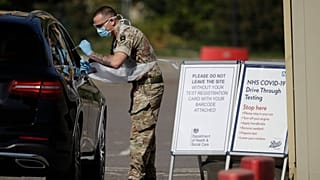 A soldier gives does a COVID-19 test at a drive-through testing centre at Chessington World of Adventures, Greater London