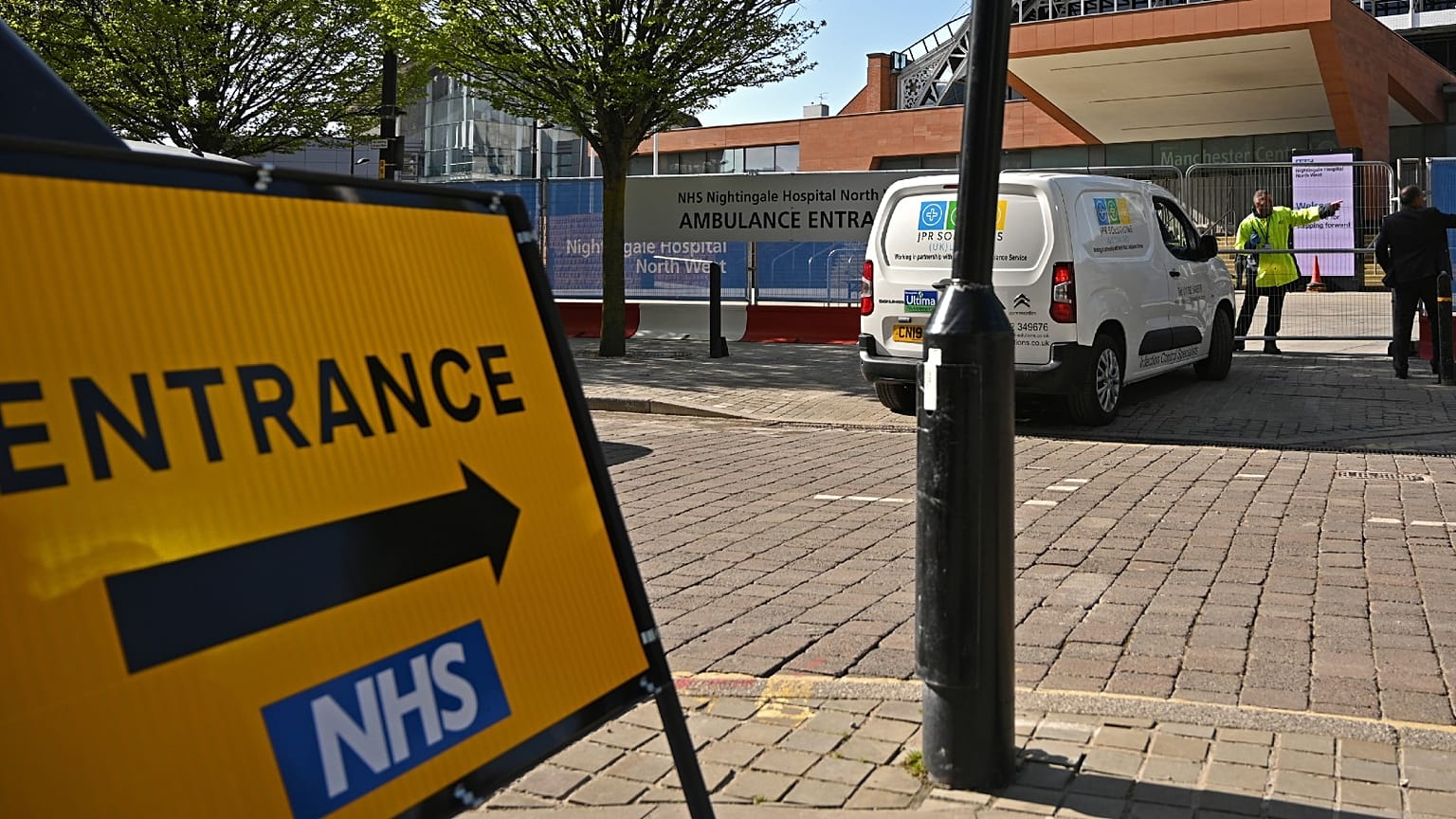 A security guard and a contractor at the gates of Manchester Central Convention Complex, converted into the "Nightingale Hospital North West", on April 13, 2020