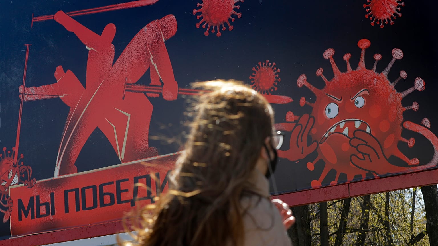 A woman walks past an advertising placard depicting the coronavirus and words reading "We will win" in Minsk, Belarus, Wednesday, April 22, 2020.