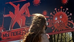 A woman walks past an advertising placard depicting the coronavirus and words reading "We will win" in Minsk, Belarus, Wednesday, April 22, 2020.