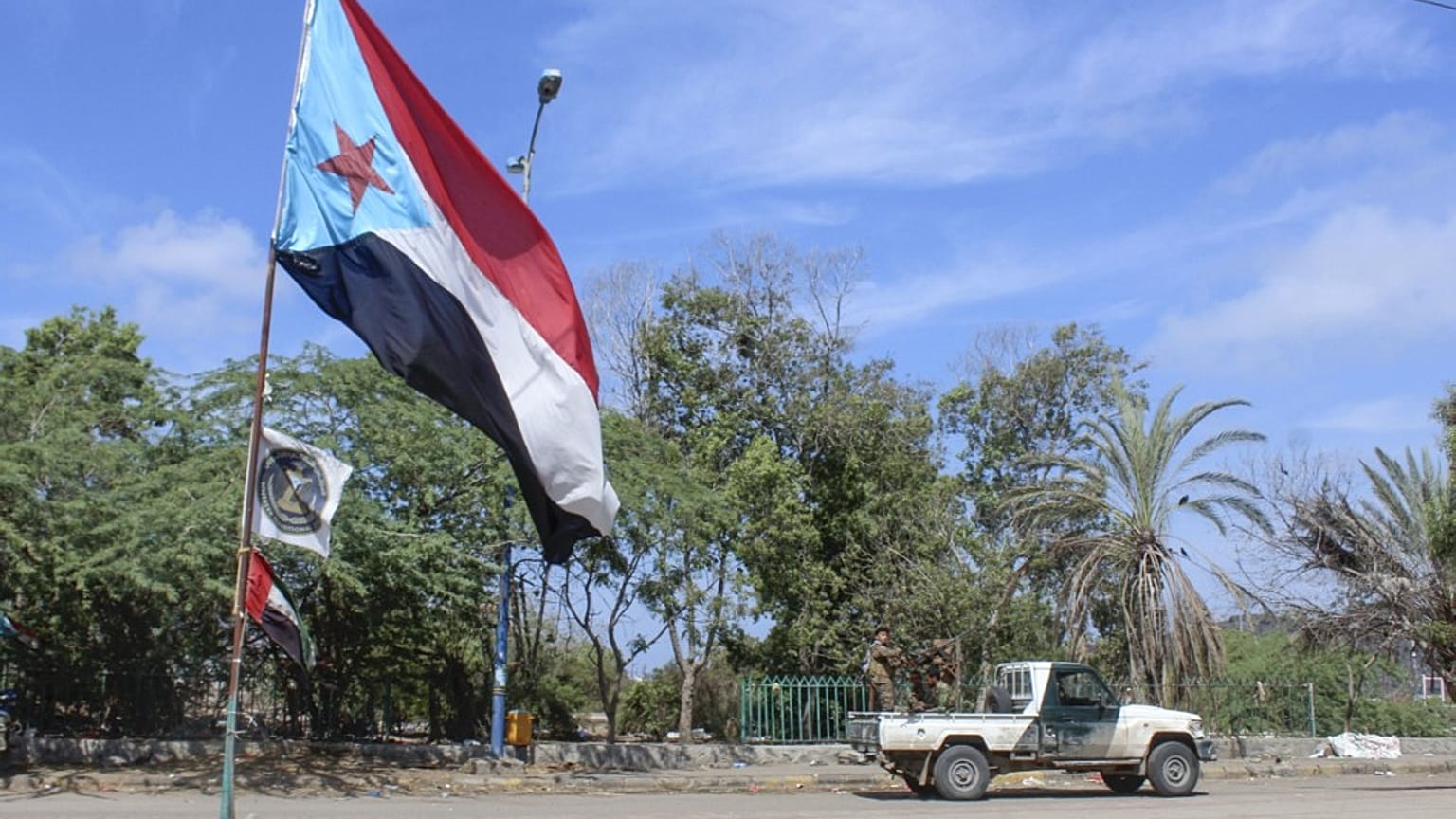 Fighters with Yemen's Southern Transitional Council (STC) drive a vehicle past a separatist flag 