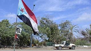 Fighters with Yemen's Southern Transitional Council (STC) drive a vehicle past a separatist flag 