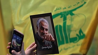 أحد مؤيدي حزب الله رافعاً صورة لقائد الحرس الثوري الإيراني السابق قاسم سليماني
