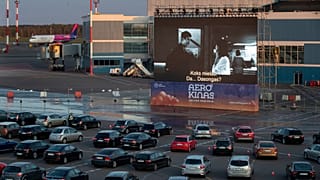 People sit in their cars watching a movie at a new drive-in cinema at the airport in Vilnius, Lithuania on April 29, 2020.