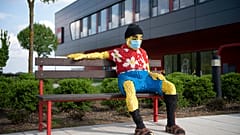 Padon ülő figura maszkban a nyíregyházi Lego-gyár előtt