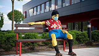 Padon ülő figura maszkban a nyíregyházi Lego-gyár előtt