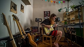 A koronavírus-járvány miatt önkéntes karanténban lévő zenész gitárján játszik budapesti otthonában 2020. április 6-án.