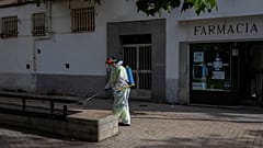Un empleado municipal con equipo de protección desinfecta mobiliario urbano en Madrid 