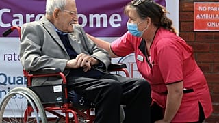 98-year-old care home resident Albert Rose talking to carer Jeanette on his birthday in Scunthorpe, UK on May 4, 2020, (Photo by Lindsey Parnaby / AFP)
