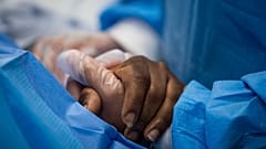 A nurse practitioner talks to a patient and holds her hand while a doctor administers an IV at Roseland Community Hospital in Chicago.