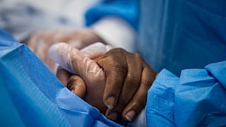 A nurse practitioner talks to a patient and holds her hand while a doctor administers an IV at Roseland Community Hospital in Chicago.