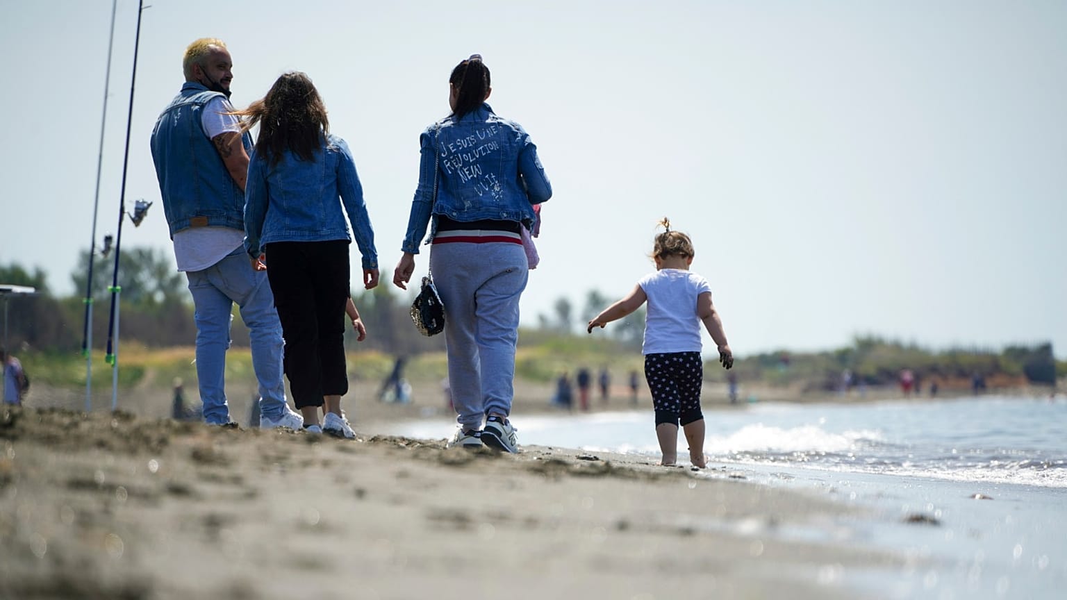 People walk along the beach of Ladispoli, a coastal town some 30 kilometers (18 miles) north of Rome, Saturday, May 9, 2020. 