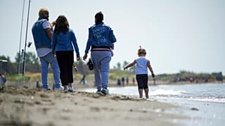 People walk along the beach of Ladispoli, a coastal town some 30 kilometers (18 miles) north of Rome, Saturday, May 9, 2020. 