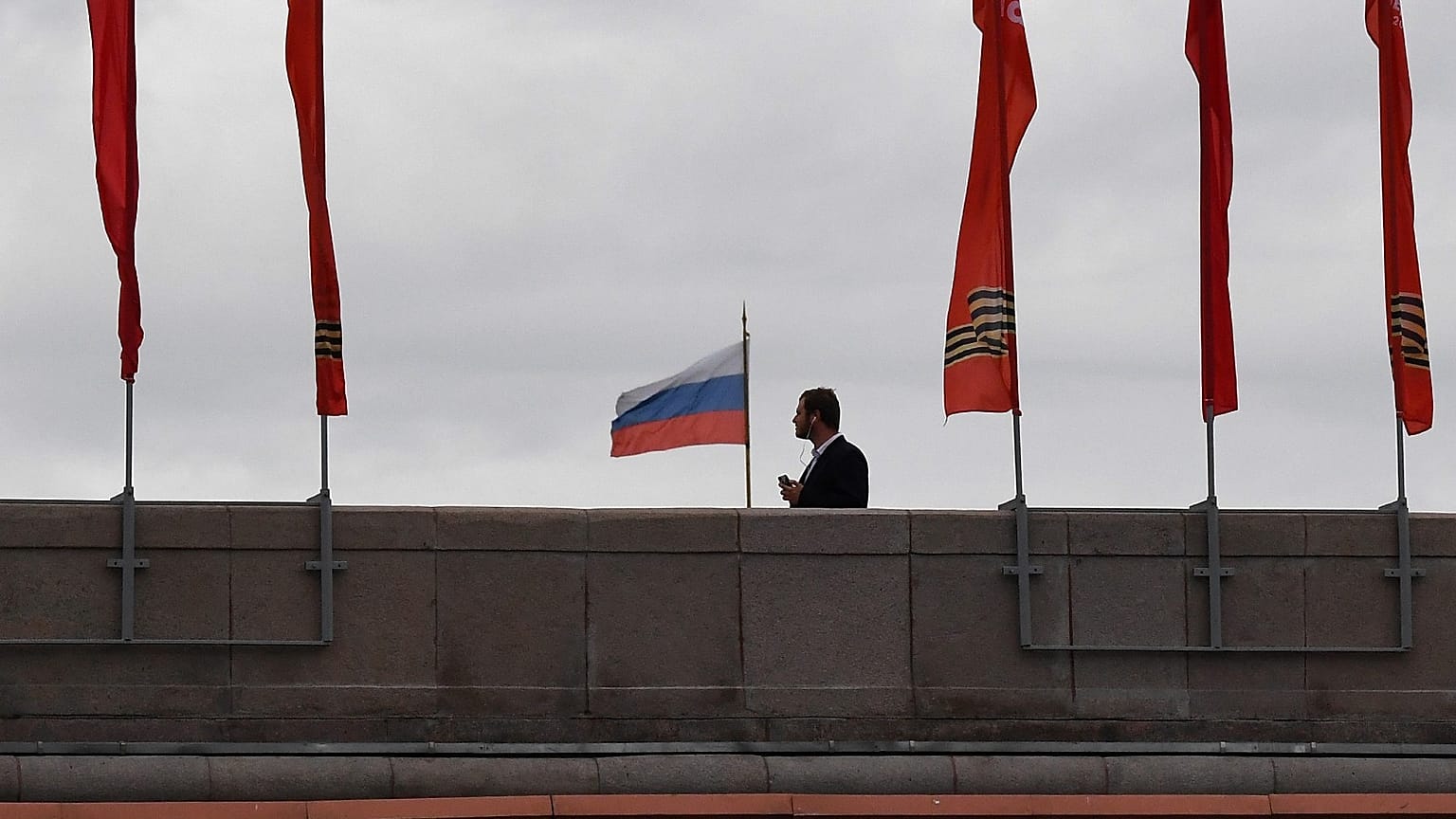 A man walks on a bridge past red banners devoted to the 75th anniversary of the victory over Nazi Germany during World War II, in downtown Moscow on May 9, 2020