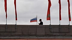 A man walks on a bridge past red banners devoted to the 75th anniversary of the victory over Nazi Germany during World War II, in downtown Moscow on May 9, 2020