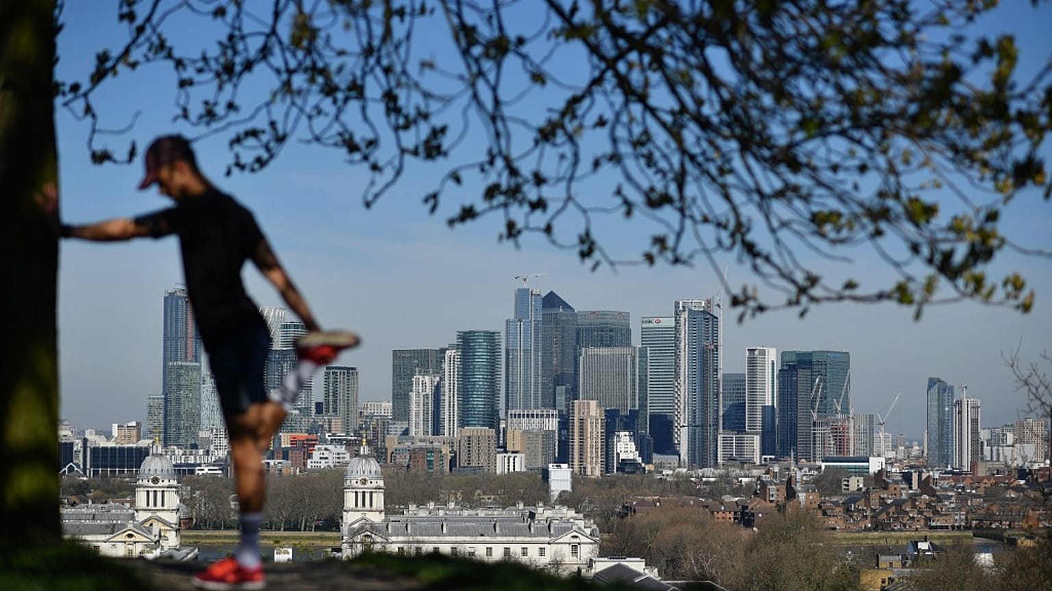 London's financial district Canary Wharf is seen as a man exercises in Greenwich Park 