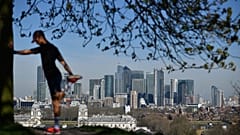 London's financial district Canary Wharf is seen as a man exercises in Greenwich Park 