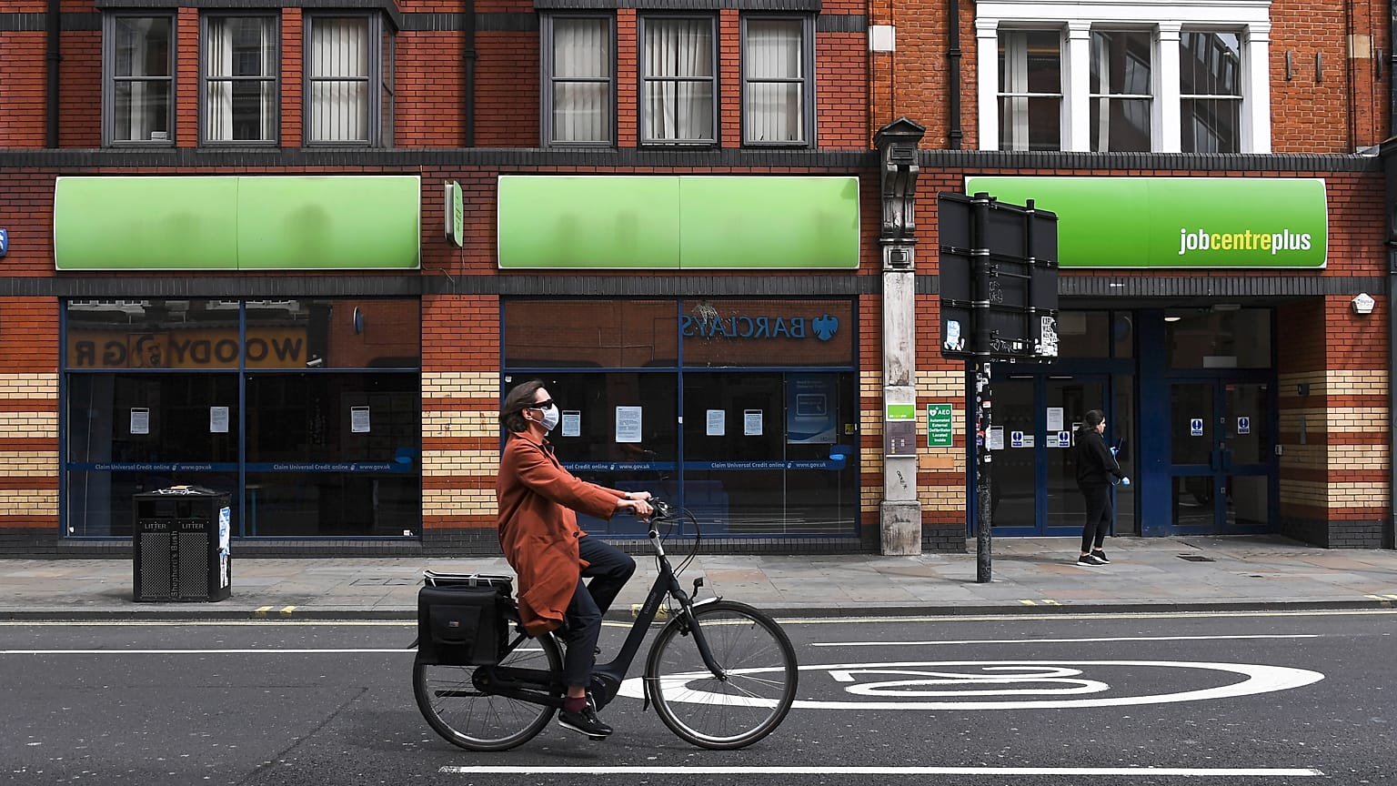 File photo: In this Thursday, April 30, 2020 photo, a woman wearing a mask to protect against coronavirus, rides a bicycle past a job centre in Shepherd's Bush, London.
