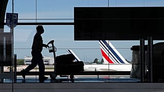 A passenger wearing a protective face mask walks in Roissy airport, north of Paris, Tuesday, May 12, 2020.