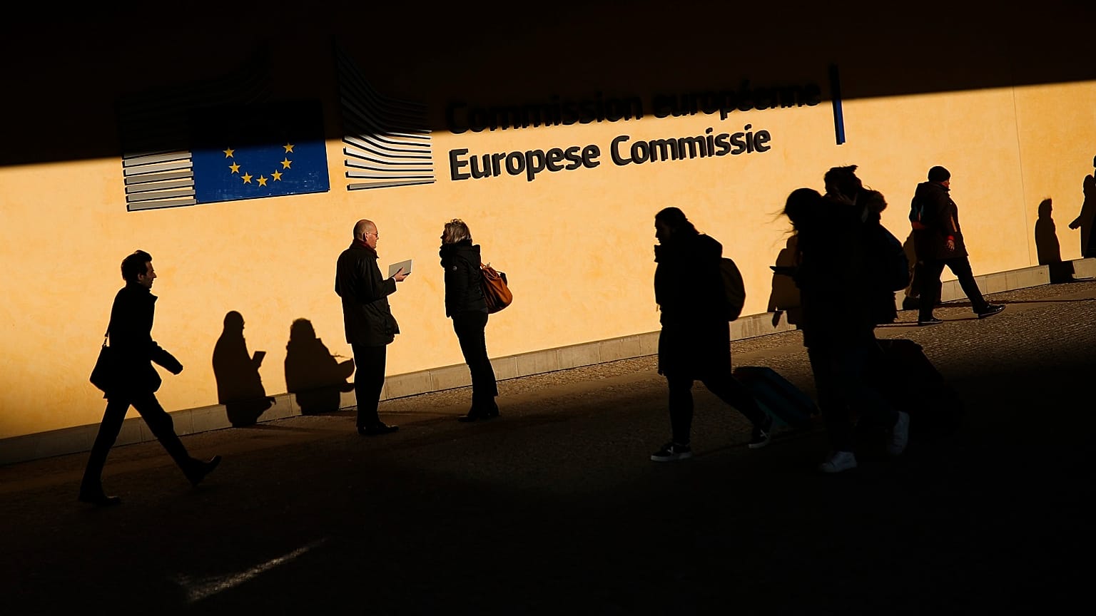 People walk past the European Commission headquarters in Brussels, Friday, Feb. 7, 2020