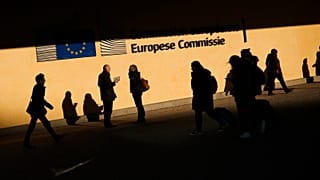 People walk past the European Commission headquarters in Brussels, Friday, Feb. 7, 2020