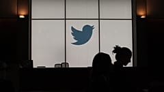 In this file photograph taken on August 14, 2019, employees walk past an illuminated Twitter logo as they leave the company's headquarters in San Francisco.