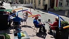 1,50 m Abstand sind weiter als man denkt: In diesem Café wird das mit ungewöhnlichem Kopfschmuck sichtbar gemacht.