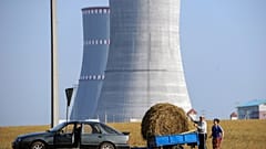 A pictureshows people transporting a bundle of straw close to the construction site of the first Belarus' nuclear power plant outside the town of Ostrovets