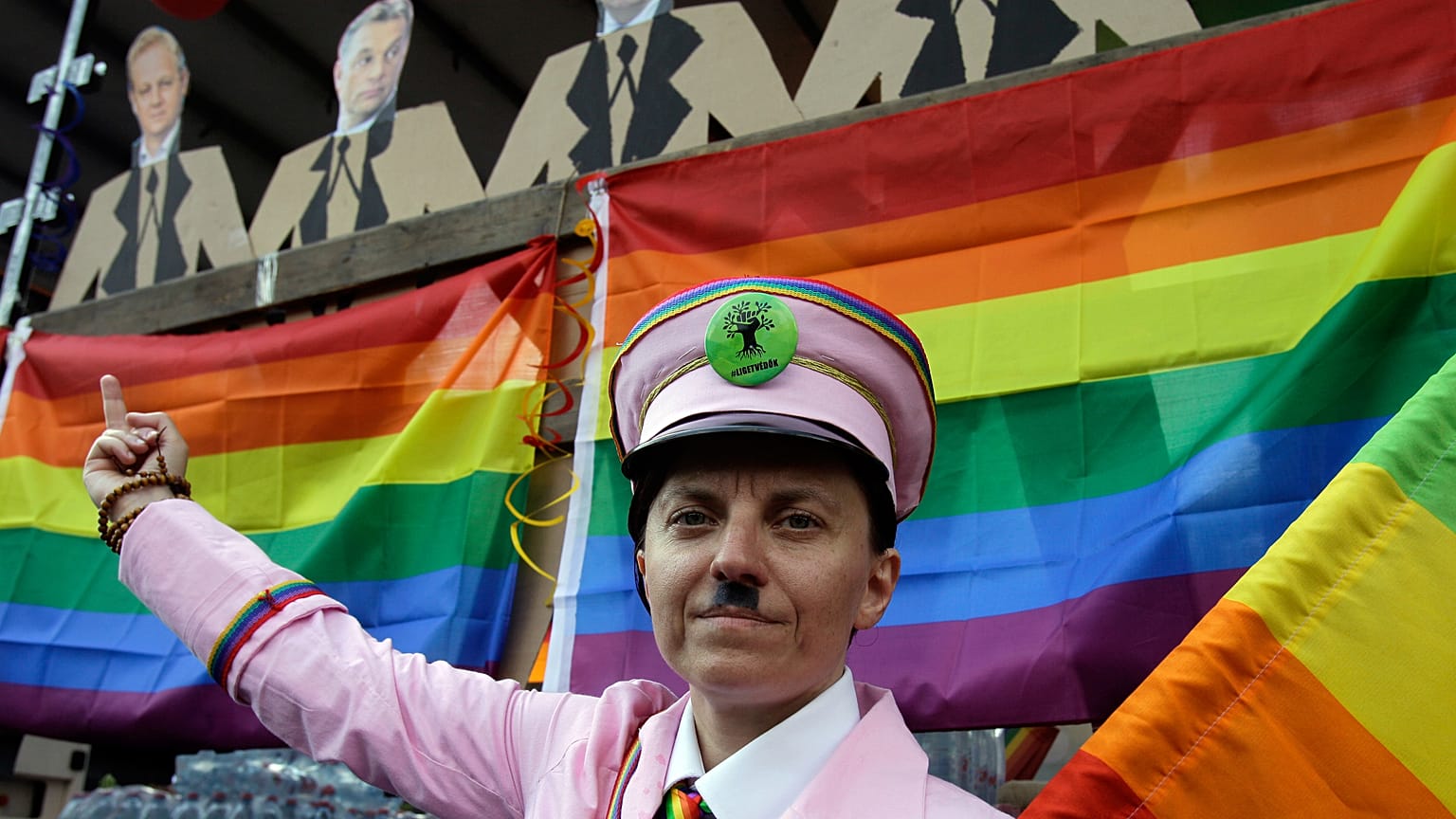 A participant gestures with a rainbow flag under the portraits of Hungarian politicans during the gay rights Pride Parade in Budapest (Photo by PETER KOHALMI / AFP)