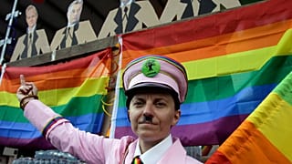 A participant gestures with a rainbow flag under the portraits of Hungarian politicans during the gay rights Pride Parade in Budapest (Photo by PETER KOHALMI / AFP)