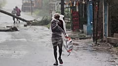 A man covers himself with a plastic sheet and walks in the rain in the Bhadrak district of the eastern Indian state of Orissa, May 20, 2020