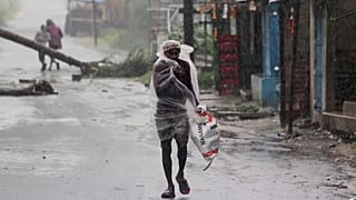 A man covers himself with a plastic sheet and walks in the rain in the Bhadrak district of the eastern Indian state of Orissa, May 20, 2020