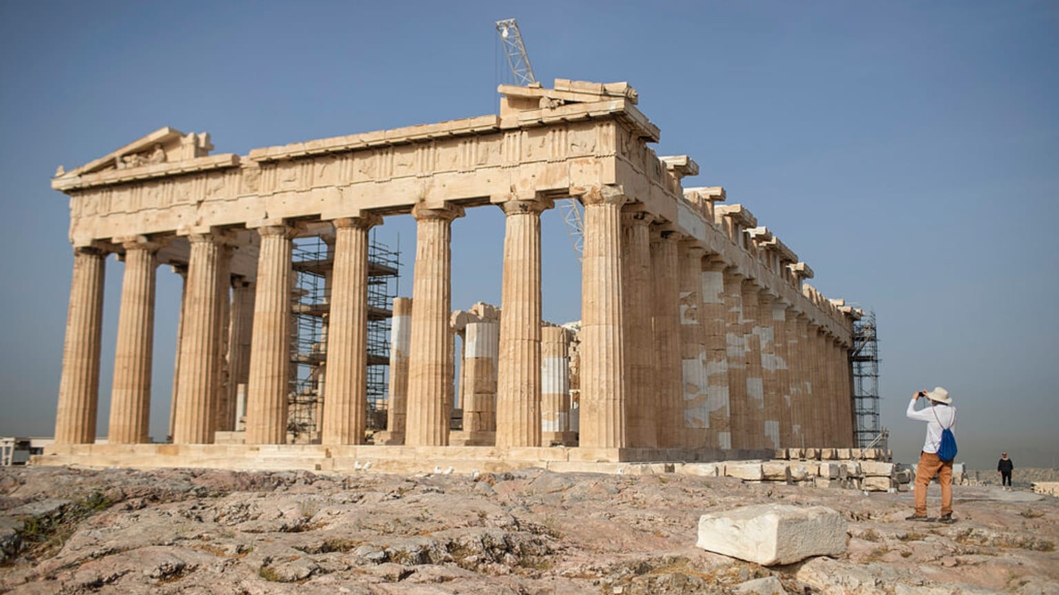 A man takes a picture next the ancient Parthenon temple at the Acropolis hill of Athens.