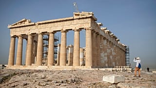 A man takes a picture next the ancient Parthenon temple at the Acropolis hill of Athens.