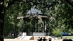 People sit on benches near the bandstand in Southwark Park in London, Tuesday, May 19, 2020