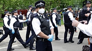 A police officer wears a face mask during a mass gathering protest organised by the group called 'UK Freedom Movement', in Hyde Park in London