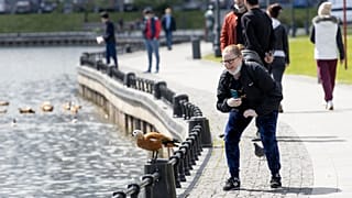 Женщина фотографирует утку в московском парке. В городе введен режим карантина.