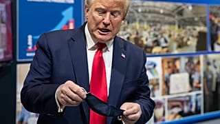 President Donald Trump holds his protective face mask 