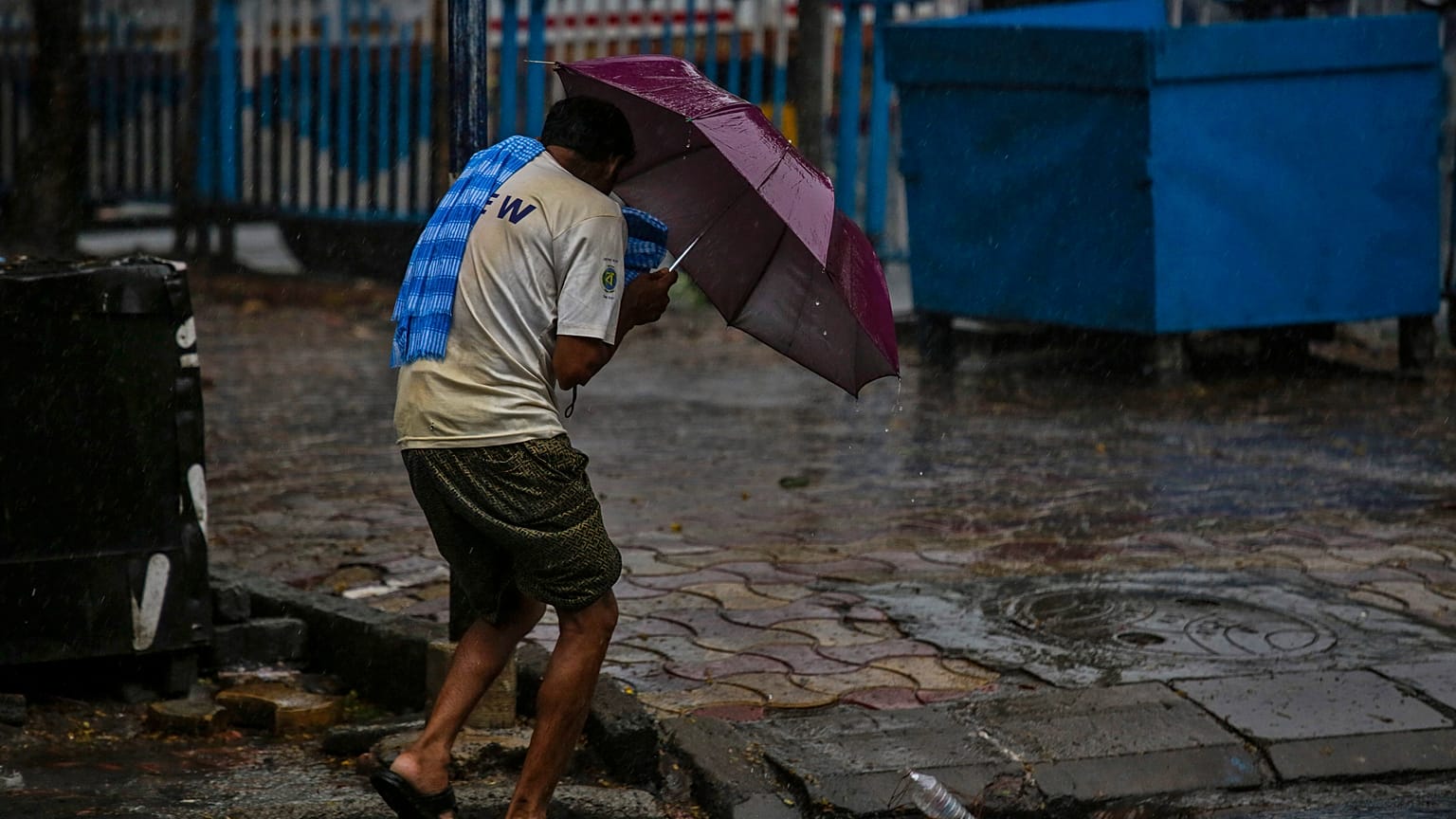 A man struggles to hold his umbrella and walk against high wind in Kolkata, India, Wednesday, May 20, 2020.
