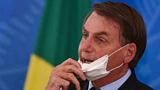 Brazil's President Jair Bolsonaro removes his mask to speak at a press conference on the new coronavirus in Brasilia, Brazil, March 18, 2020