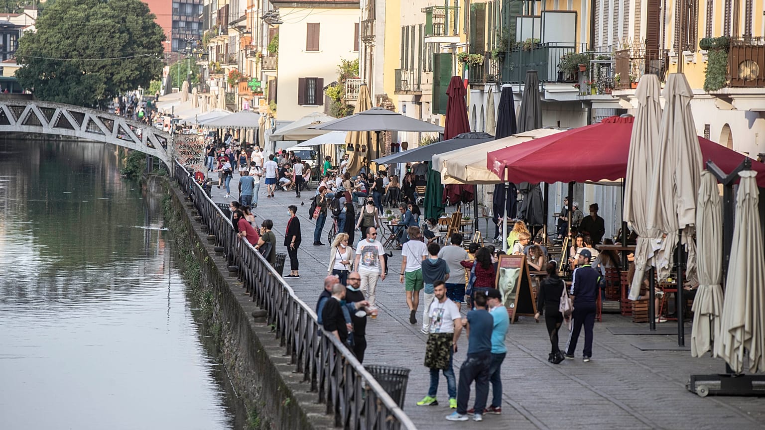 People walk along the Naviglio grande canal in Milan, Italy, Monday, May 18, 2020