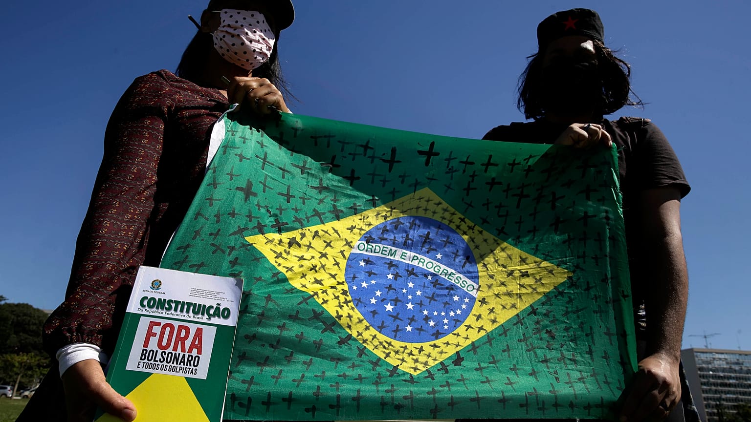 Demonstrators hold a national flag marked with black crosses during a protest demanding President Jair Bolsonaro be impeached
