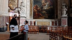 Un prêtre parle avec une croyante avant une message en l'église Saint Roch à Paris, le 23 mai 2020